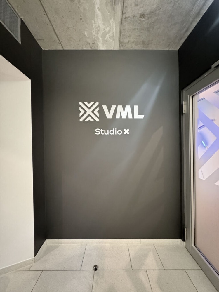 Schwarzglänzendes VML-Logo auf anthrazitfarbener Wand